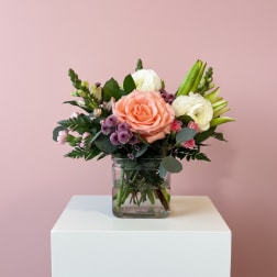 Bouquet of peach and white flowers in a clear glass vase