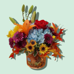 Autumn bouquet with red rose, blue hydrangea, lilies, and mums in a pumpkin vase