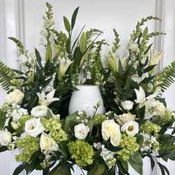 White floral arrangement with lilies, roses, and green hydrangeas in a vase