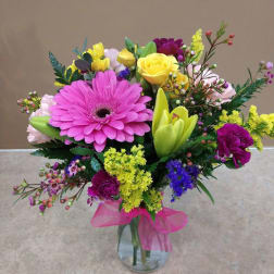 Colorful mixed bouquet in a clear glass vase with a pink ribbon