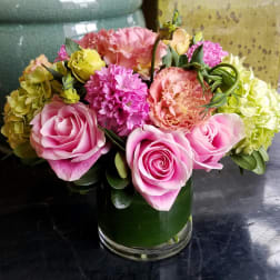 Pink roses and mixed blooms arranged in a glass vase