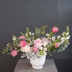 Pink and white flowers arranged in a white vase.