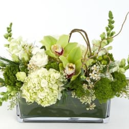 Green and white floral arrangement in a rectangular glass vase