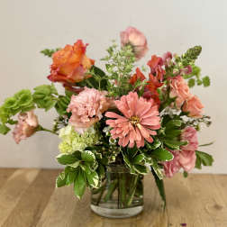 Mixed pink and orange flowers arranged in a clear glass vase