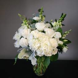 White roses and hydrangeas in a clear glass vase