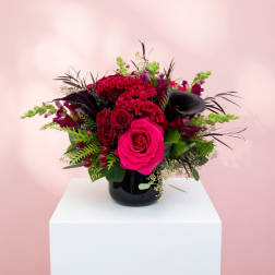 Pink and red floral arrangement in a black vase