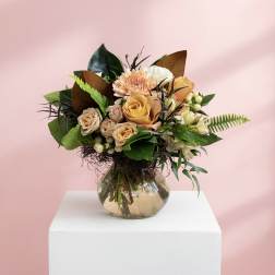 Mixed bouquet of peach and cream roses in a glass vase