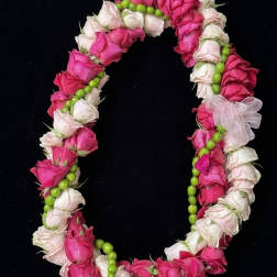 Pink and white rose lei with green beads on a black background