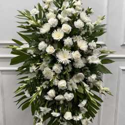 Tall white funeral spray with roses, chrysanthemums, and lilies