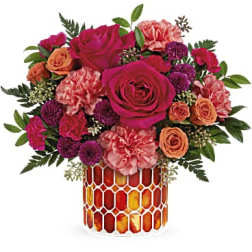 Bouquet of pink and orange flowers in a patterned glass vase