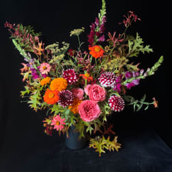Colorful mixed bouquet in a dark vase with pink, orange, and burgundy blooms
