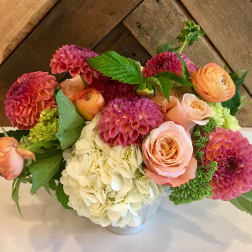 Pink and peach flowers arranged in a white vase