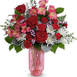 Bouquet of red roses, pink alstroemeria, and white daisies in a pink glass vase