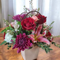Mixed flower arrangement in a white handled box with red roses and pink lilies