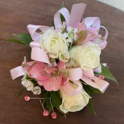 Small pink and white floral corsage with ribbon loops