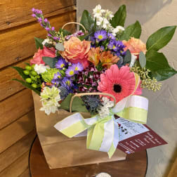Mixed bouquet in a paper bag with a ribbon bow