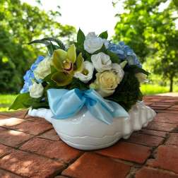 Bouquet of white and blue flowers in a white ceramic bowl with a blue ribbon