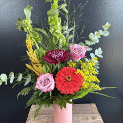 Mixed bouquet in a pink vase with roses, a red zinnia, and yellow filler flowers
