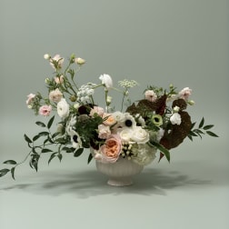 Mixed pastel floral arrangement in a white pedestal vase