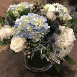 Blue hydrangea and white rose bouquet in a glass vase