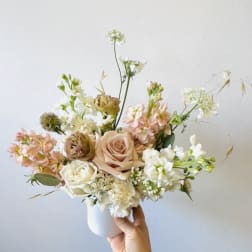 Pastel bouquet of roses and white blooms in a white vase