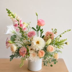 Pastel floral arrangement in a white vase with pink and cream blooms