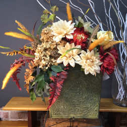 Autumn floral arrangement with cream and red blooms in a green container