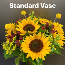 Sunflower arrangement in a vase with yellow accents and red berries