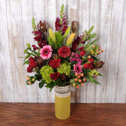 Tall mixed bouquet in a yellow vase with red, pink, and green blooms
