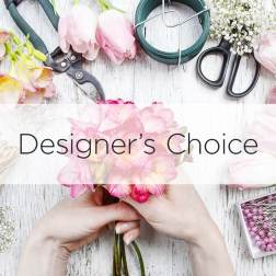 Hands holding pink flowers with floral tools and supplies on a white table