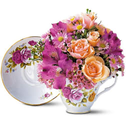 Bouquet of peach and purple flowers in a floral teacup