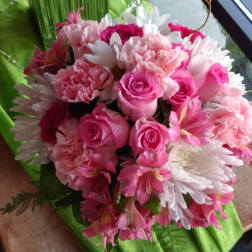 Pink roses and white daisies arranged in a green-wrapped bouquet
