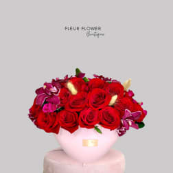 Red roses and purple orchids arranged in a pink vase