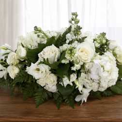 Low white floral arrangement with roses and hydrangeas on a table
