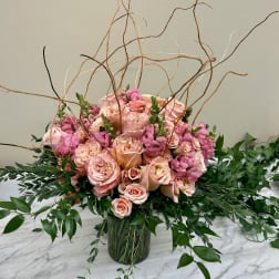 Pink roses and snapdragons in a glass vase with curly branches