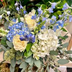 Blue and white floral arrangement with roses, hydrangeas, and delphinium