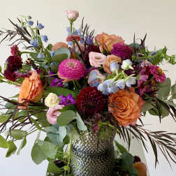 Mixed bouquet of orange, pink, and purple flowers in a textured vase