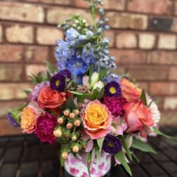 Colorful mixed flower arrangement in a pink patterned container