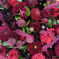 Dense bouquet of burgundy and pink flowers with green leaves
