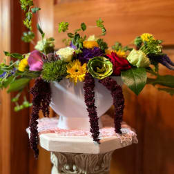Colorful mixed flower arrangement in a white pedestal vase