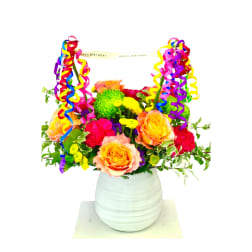Colorful birthday bouquet in a white vase with ribbon streamers