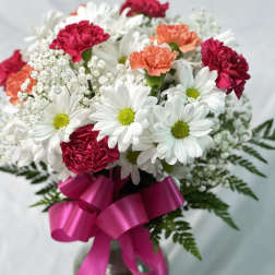 Bouquet of white daisies and pink carnations with a magenta ribbon in a vase