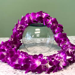 Purple orchid lei draped around a clear glass bowl