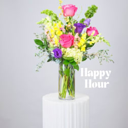 Mixed bouquet of pink, purple, and yellow flowers in a clear glass vase