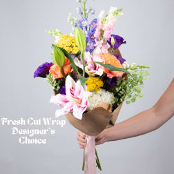 Hand-tied bouquet of mixed flowers in brown paper with a pink ribbon