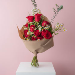 Bouquet of red roses and small white daisies wrapped in brown paper
