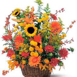 Autumn flower arrangement in a wicker basket with sunflowers and orange blooms