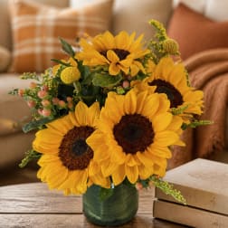 Sunflower arrangement in a green glass vase on a table