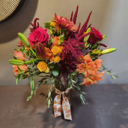 Mixed bouquet in a glass vase with roses, lilies, and orange blooms