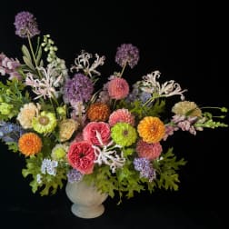 Colorful mixed flower arrangement in a white vase on a black background